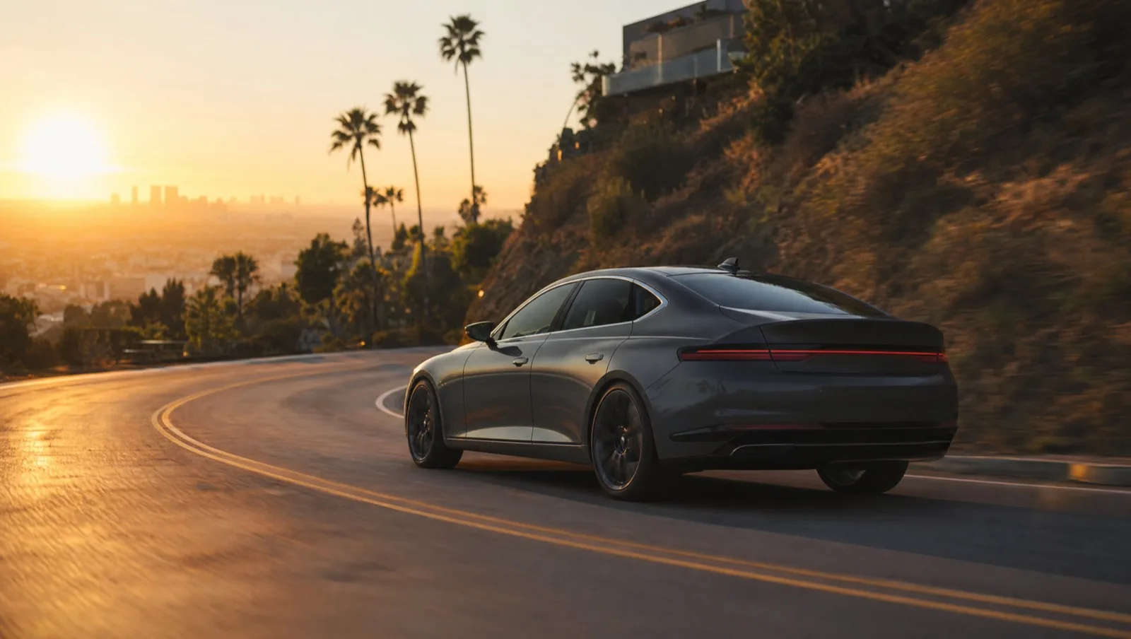 Luxury sedan driving a Los Angeles hillside road at sunset